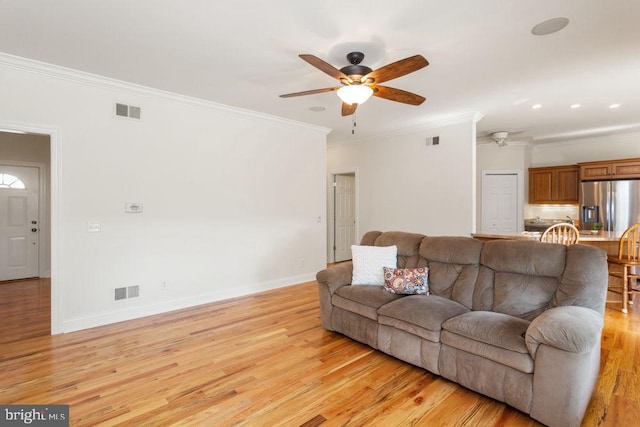 living area with ceiling fan, ornamental molding, light wood-style flooring, and visible vents
