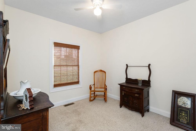 sitting room with visible vents, baseboards, ceiling fan, and light colored carpet