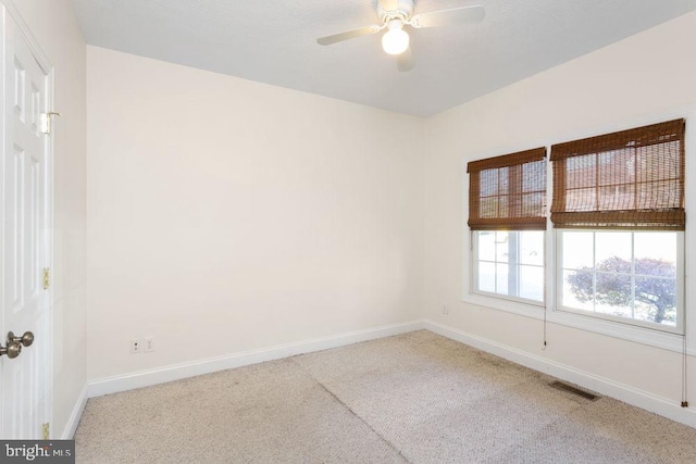 carpeted empty room with baseboards, a ceiling fan, and visible vents