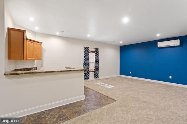 kitchen featuring baseboards, dark colored carpet, an AC wall unit, recessed lighting, and a sink