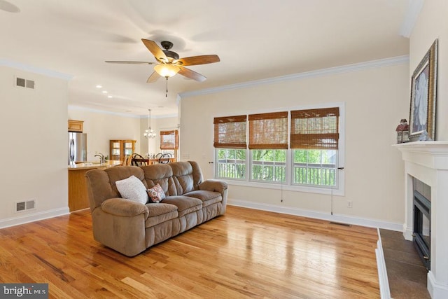 living room with visible vents, a glass covered fireplace, and light wood finished floors