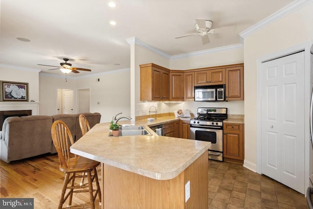 kitchen featuring a sink, a peninsula, light countertops, a ceiling fan, and stainless steel appliances