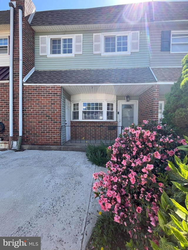 view of exterior entry featuring brick siding and roof with shingles