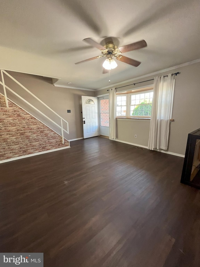 unfurnished living room featuring stairs, a ceiling fan, baseboards, and brick wall