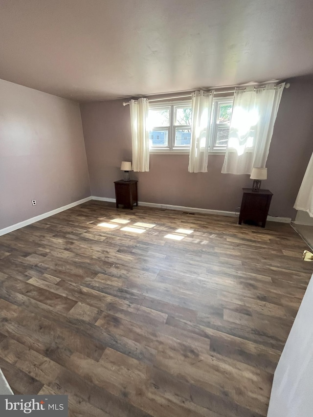 unfurnished room with baseboards and dark wood-style flooring