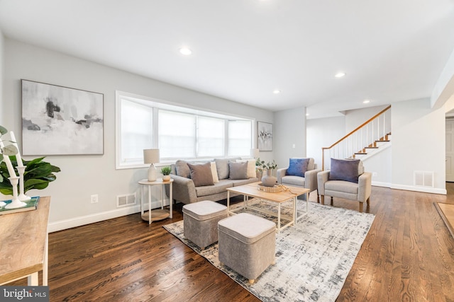 living area with baseboards, visible vents, wood finished floors, and stairway