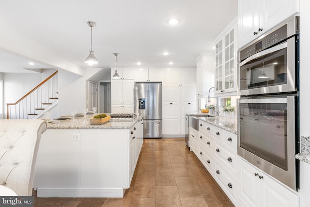 kitchen featuring a sink, appliances with stainless steel finishes, white cabinets, and hanging light fixtures