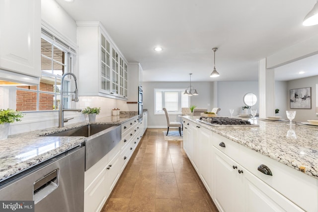 kitchen featuring white cabinets, a sink, stainless steel appliances, tasteful backsplash, and glass insert cabinets