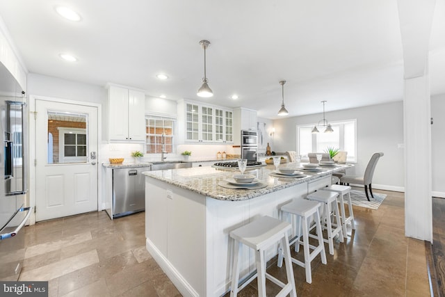 kitchen with a kitchen island, glass insert cabinets, white cabinets, a sink, and stainless steel appliances