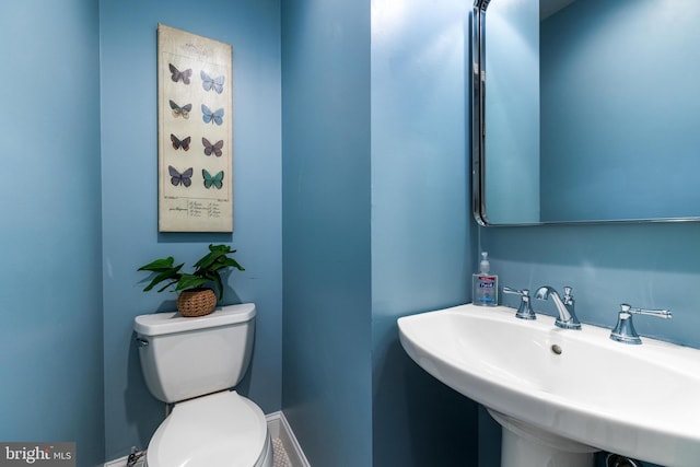 half bathroom featuring a sink, baseboards, and toilet