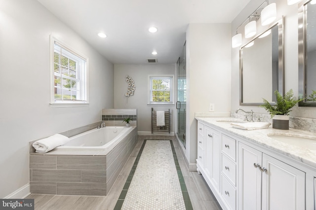 bathroom with double vanity, a bath, a sink, baseboards, and recessed lighting