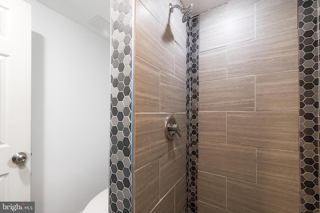 bathroom featuring a tile shower and toilet