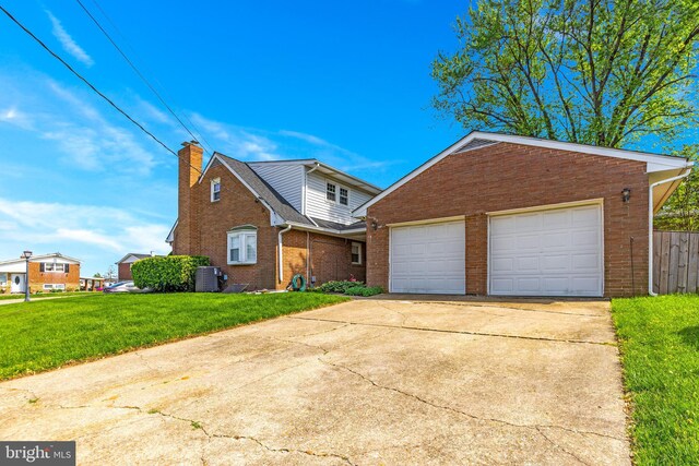 view of front of house with brick siding, a garage, a front yard, central AC unit, and concrete driveway