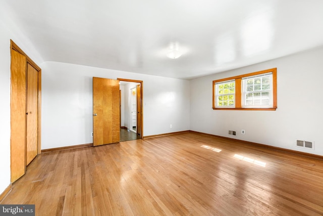 unfurnished bedroom with baseboards, light wood-type flooring, and visible vents