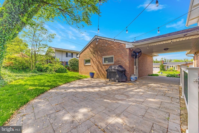 rear view of property with brick siding, a patio, and a lawn