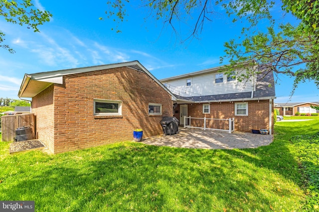 back of house with a yard, a patio area, and brick siding