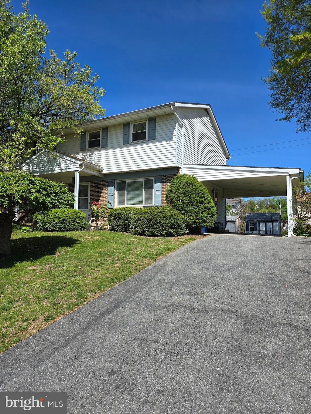 traditional home with brick siding, driveway, a front yard, and a carport