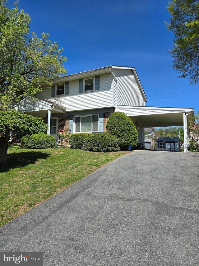 traditional home with brick siding, driveway, a front yard, and a carport