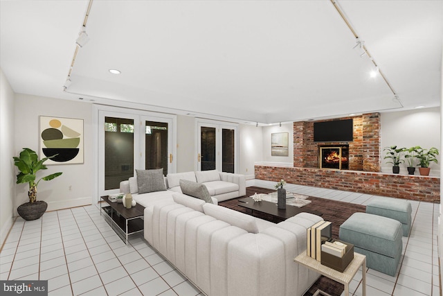 living area with light tile patterned floors, track lighting, baseboards, and a brick fireplace