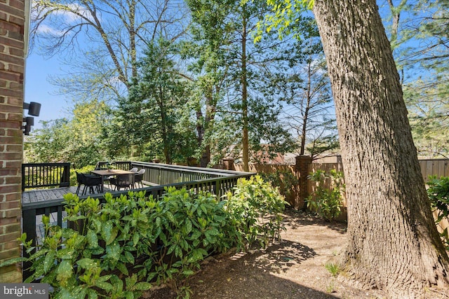 view of yard featuring outdoor dining space, a wooden deck, and fence