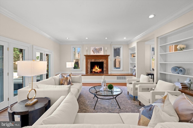 living room with crown molding, visible vents, wood finished floors, recessed lighting, and a premium fireplace