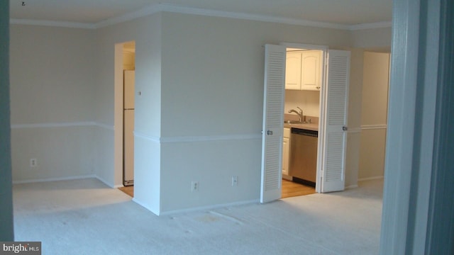 unfurnished bedroom with crown molding, freestanding refrigerator, a sink, and light colored carpet