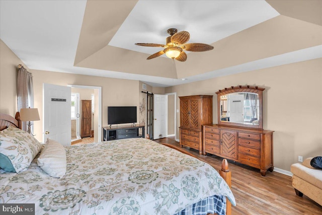 bedroom featuring a ceiling fan, visible vents, wood finished floors, baseboards, and a raised ceiling