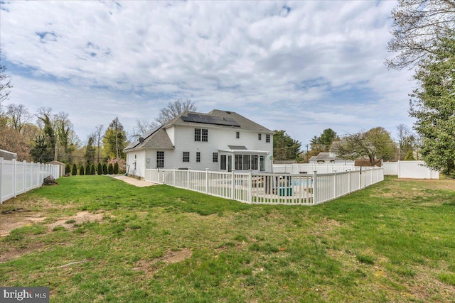 rear view of house featuring a fenced in pool, a fenced backyard, solar panels, a patio area, and a yard