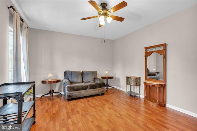 sitting room featuring baseboards, a ceiling fan, and light wood-type flooring