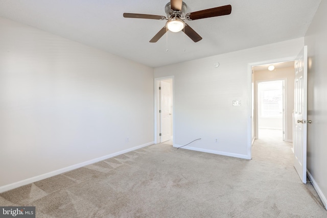 unfurnished room with baseboards, a ceiling fan, and light colored carpet