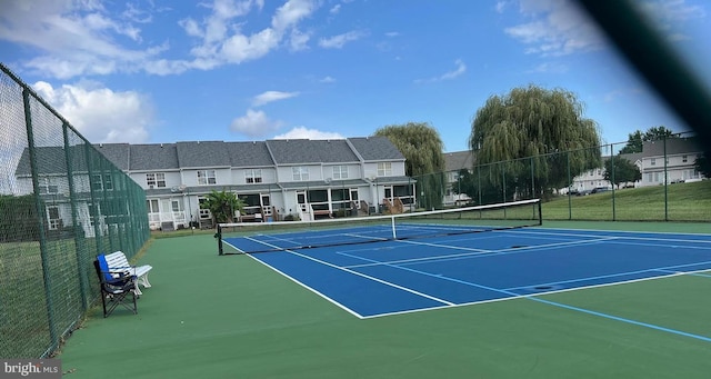 view of tennis court featuring community basketball court and fence