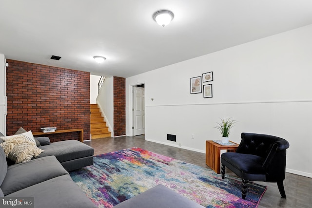 living room featuring stairs, baseboards, and brick wall