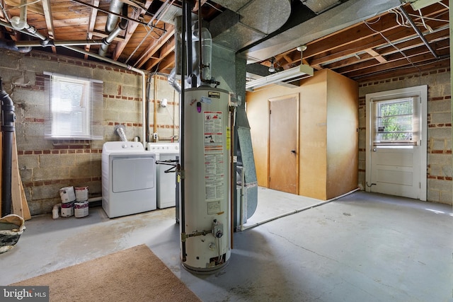 below grade area with water heater, washer and clothes dryer, and concrete block wall