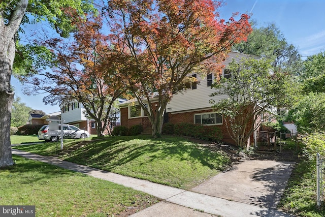 view of front of property with a front lawn, brick siding, and concrete driveway