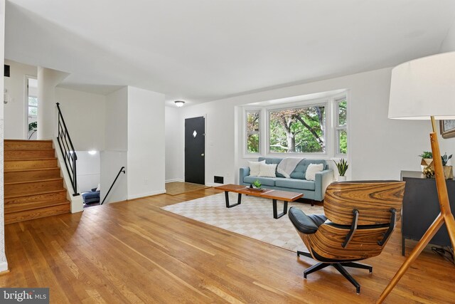 living room with wood finished floors, plenty of natural light, and stairs