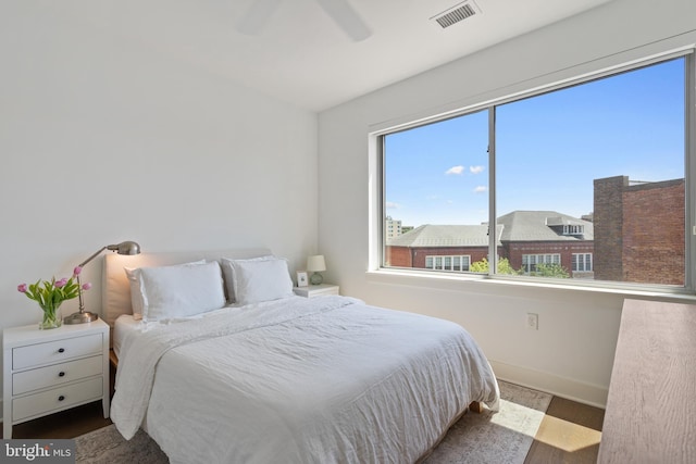 bedroom with baseboards, ceiling fan, wood finished floors, and visible vents