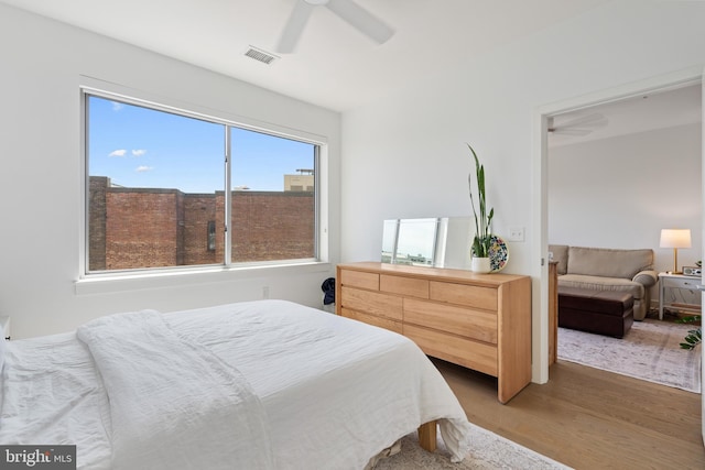 bedroom featuring ceiling fan, visible vents, and wood finished floors