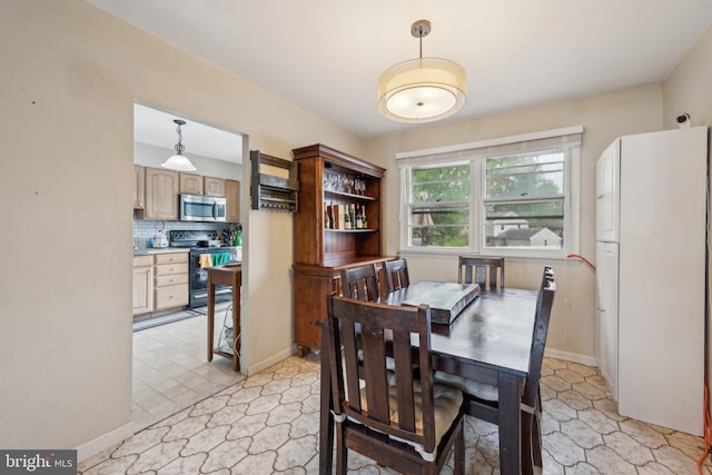 dining room featuring baseboards and light floors