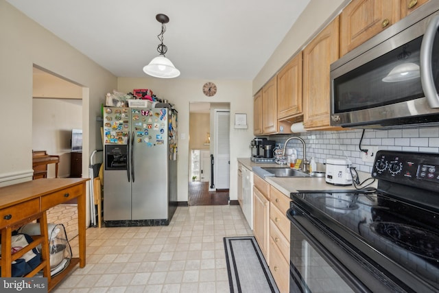 kitchen with appliances with stainless steel finishes, a sink, decorative backsplash, light countertops, and hanging light fixtures