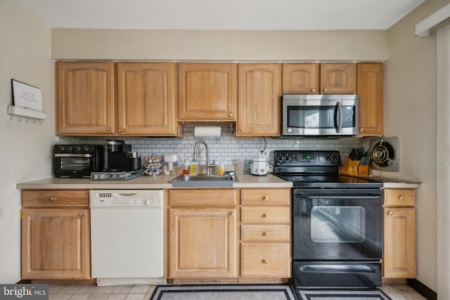 kitchen featuring stainless steel microwave, dishwasher, a sink, black range with electric cooktop, and decorative backsplash