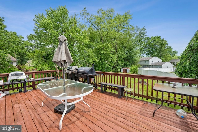 wooden deck with area for grilling, outdoor dining area, an outdoor structure, and a shed