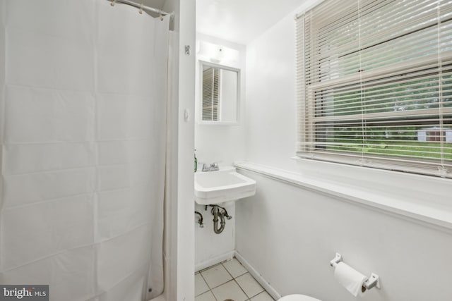 full bathroom featuring curtained shower, tile patterned floors, baseboards, and a sink