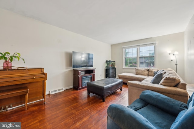 living room featuring wood finished floors, a glass covered fireplace, and baseboards