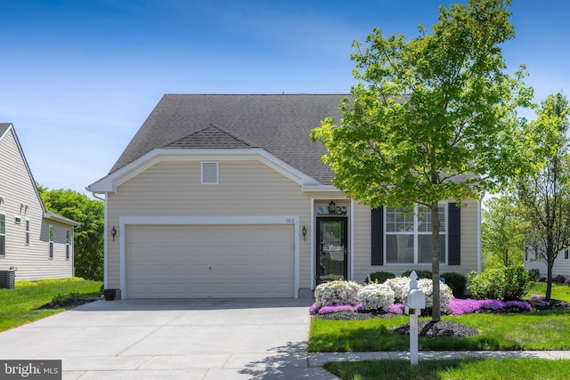 view of front of house featuring an attached garage, driveway, a shingled roof, and central AC unit