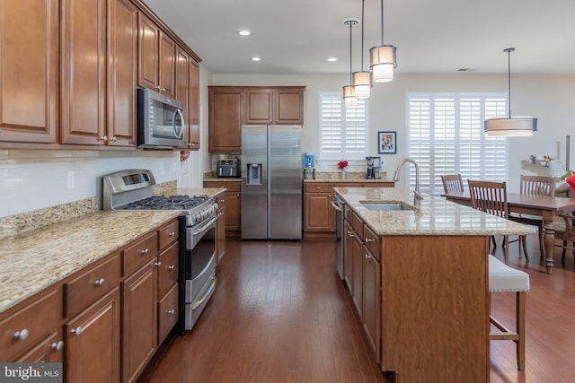 kitchen with stainless steel appliances, a breakfast bar, a sink, and dark wood-type flooring