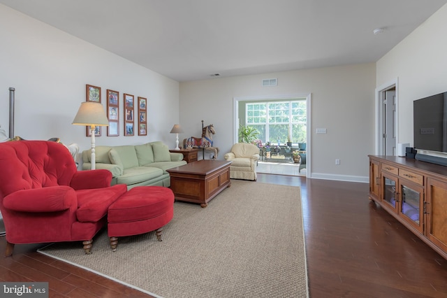 living room featuring visible vents, baseboards, and wood finished floors
