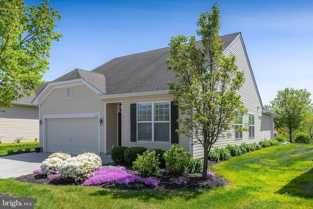 view of front of home featuring concrete driveway, a shingled roof, a front yard, and a garage
