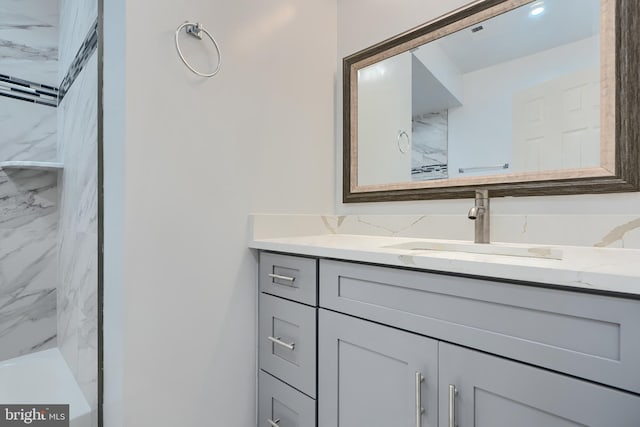 bathroom with a marble finish shower and vanity