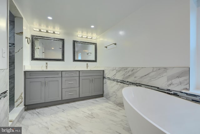bathroom featuring a sink, marble finish floor, double vanity, and a freestanding bath