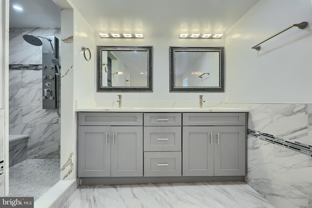 bathroom with a sink, a tile shower, double vanity, and marble finish floor